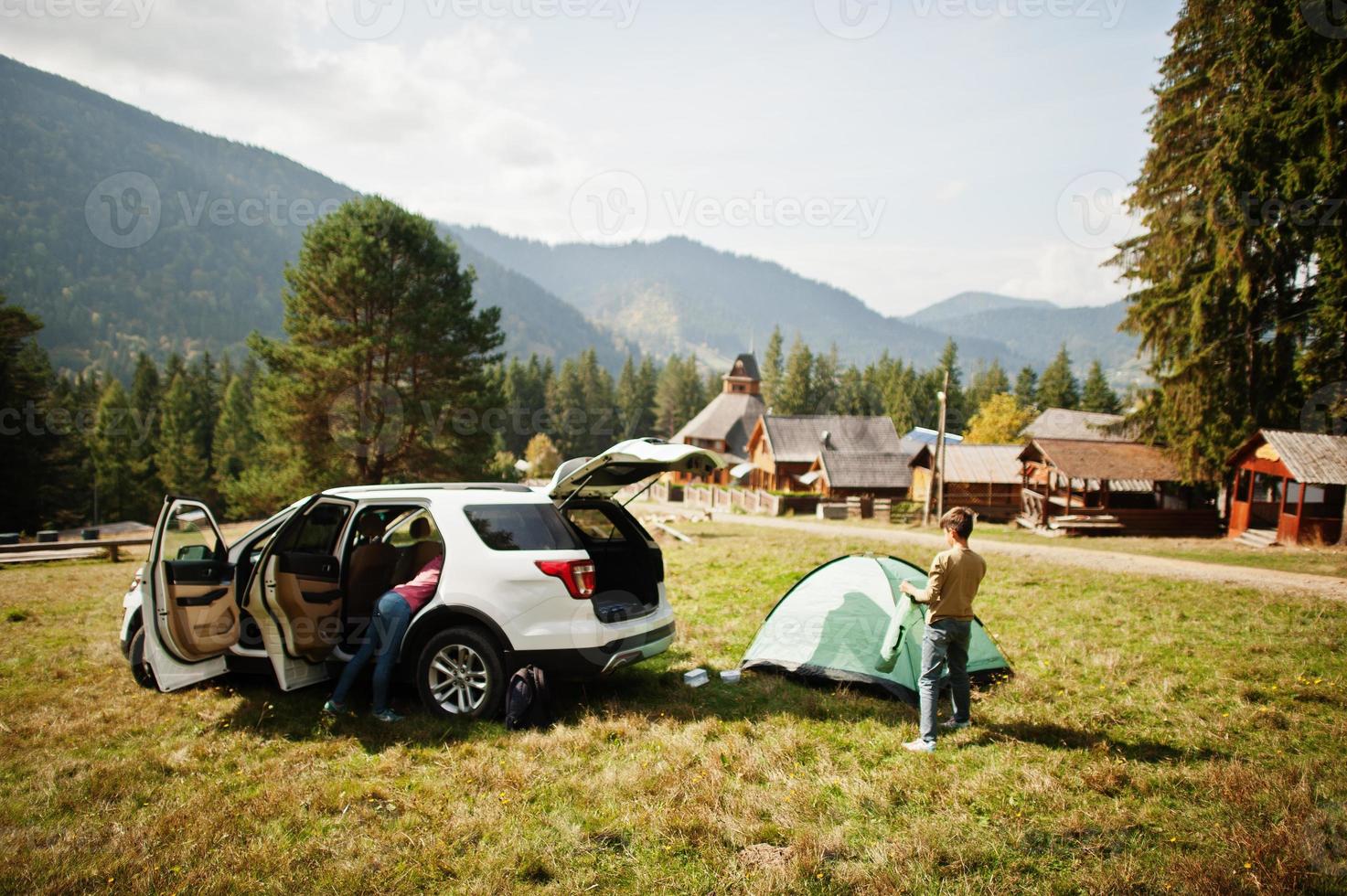 pojken sätter upp ett tält. reser med bil i bergen, atmosfär koncept. foto