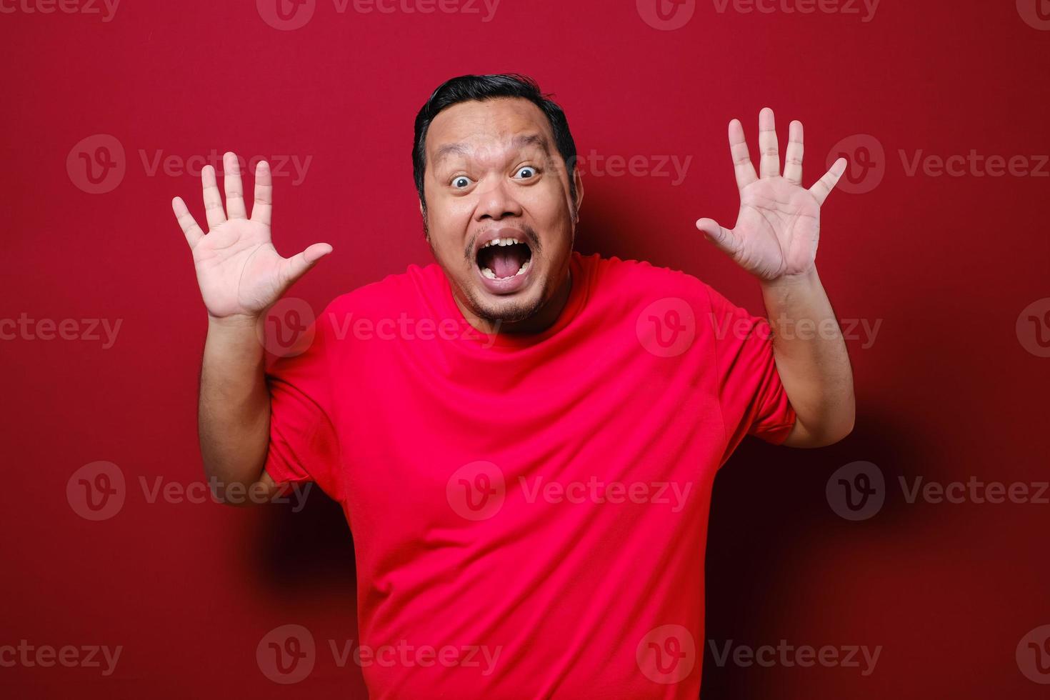 asiatisk man känner chock och överraskning med alltför ansiktsuttryck över röd bakgrund foto