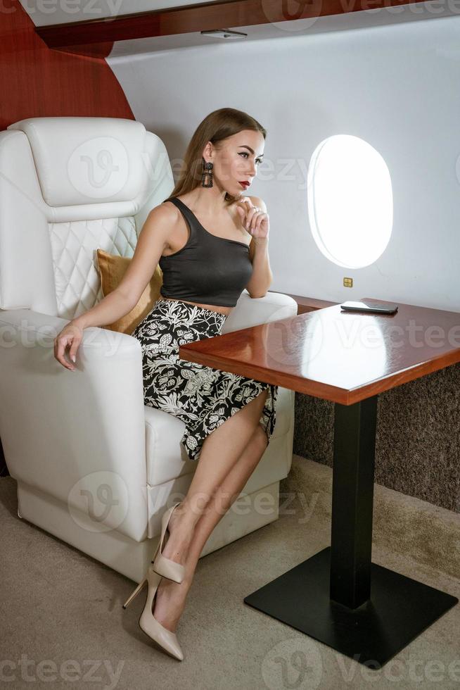 vacker brunett kvinna sitter i en privat flygstol foto