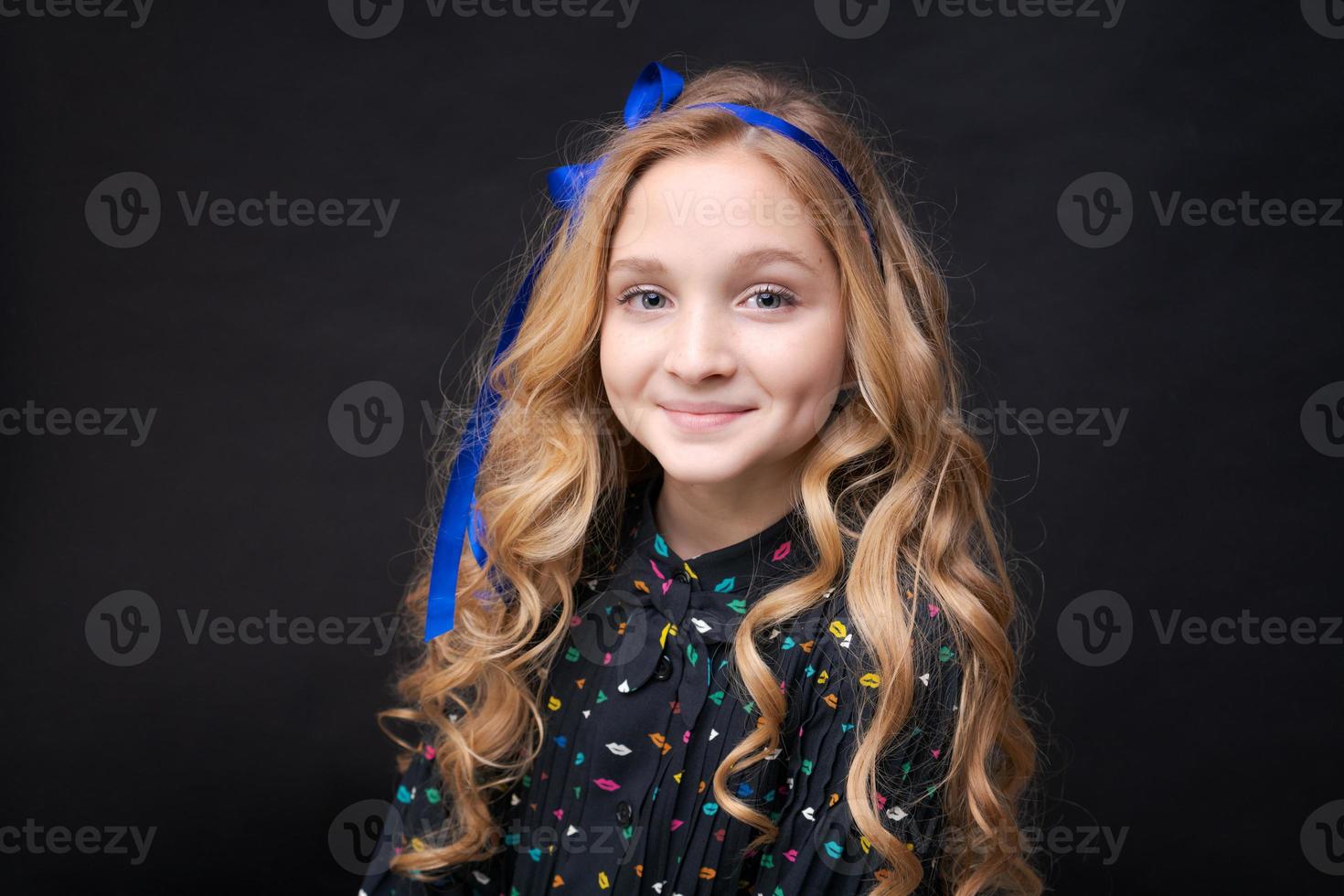 leende söt liten kaukasisk flicka 12-10 poserar på svart bakgrund foto