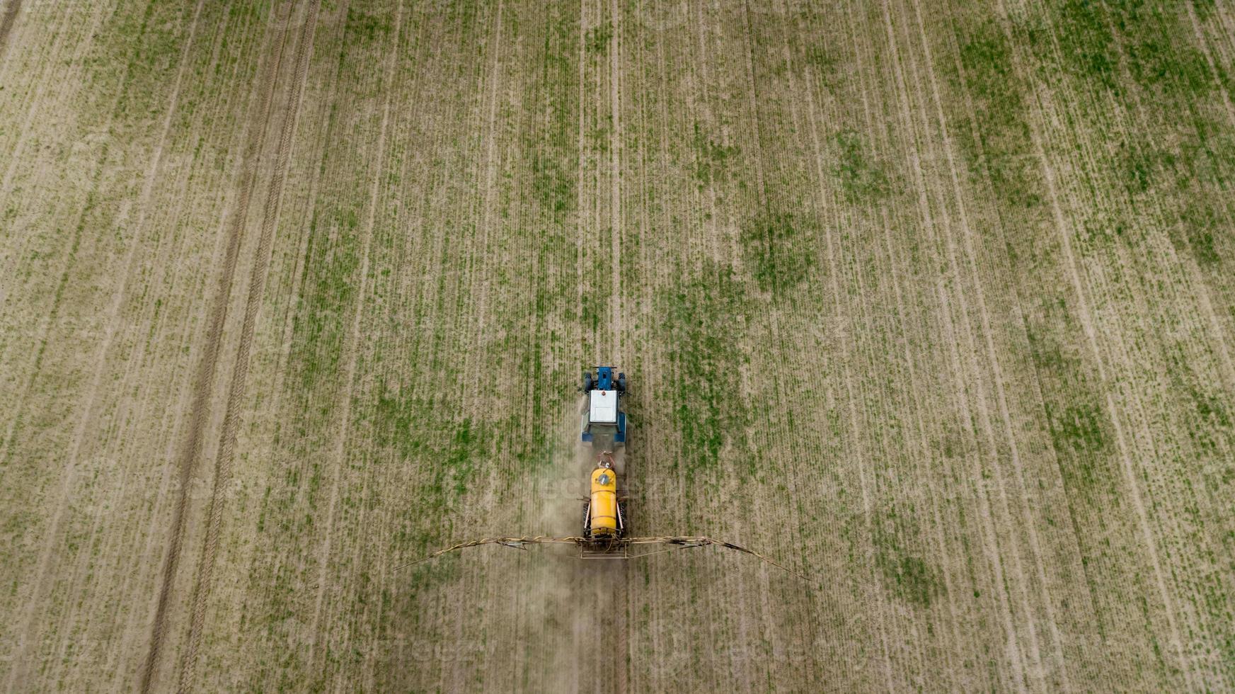 Flygfoto av jordbrukstraktor som plöjer och sprutar på fältet foto