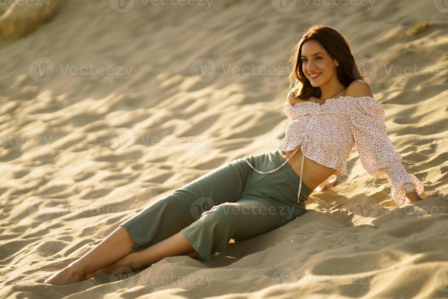 attraktiv kvinna sitter på sanden på stranden foto