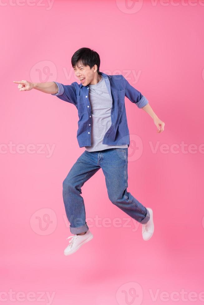 ung asiatisk man hoppar på blå bakgrund foto