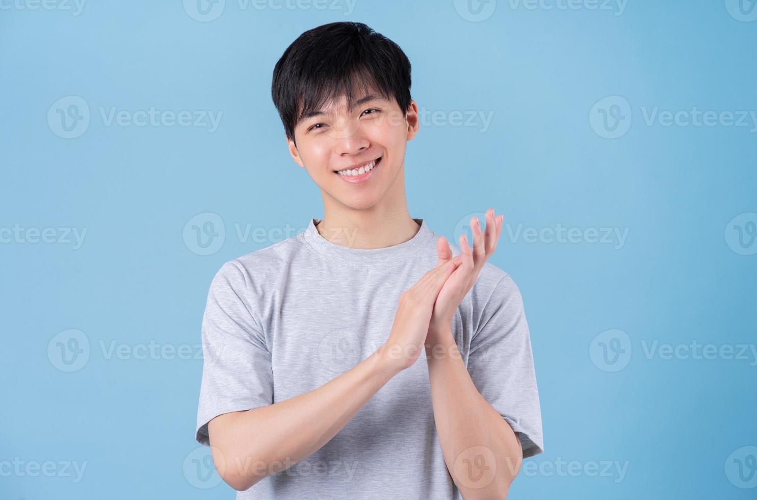 ung asiatisk man poserar på blå bakgrund foto
