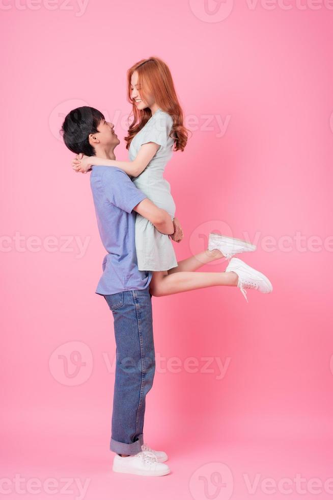 unga asiatiska par poserar på rosa bakgrund foto