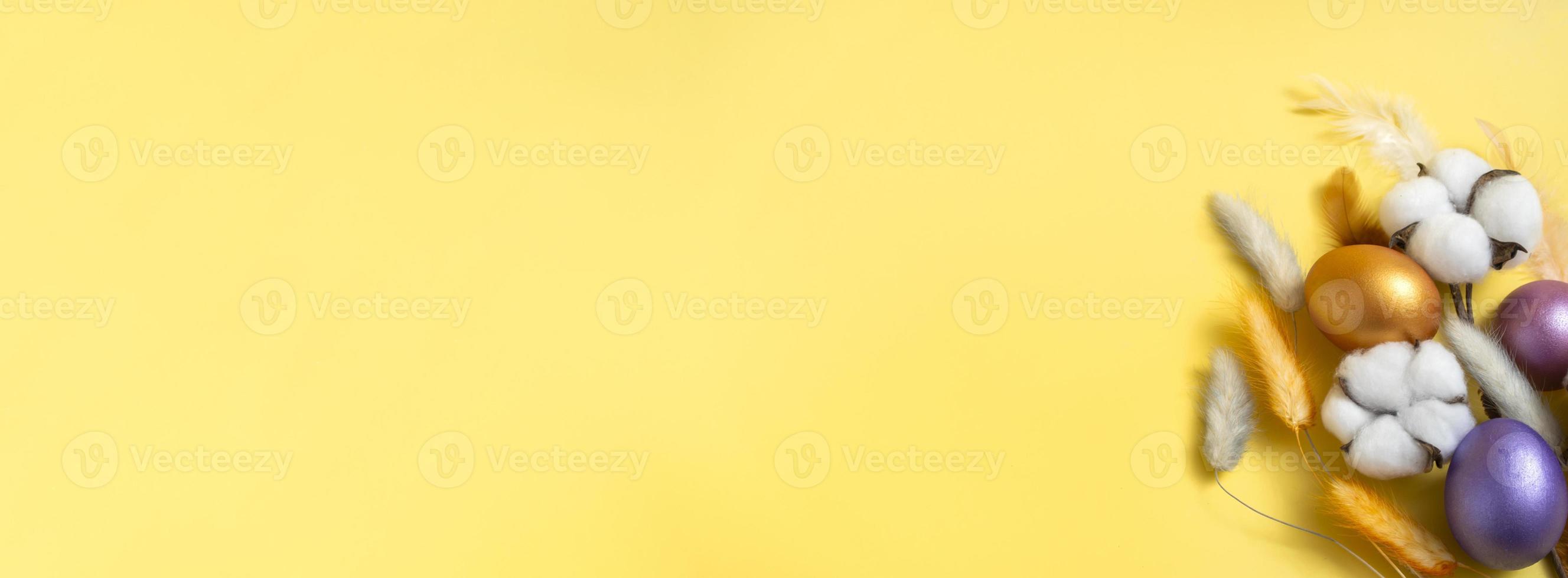 närbild ovanifrån av påsk banner. påskägg, bomull och lagurus på gul bakgrund. banner med kopia utrymme foto