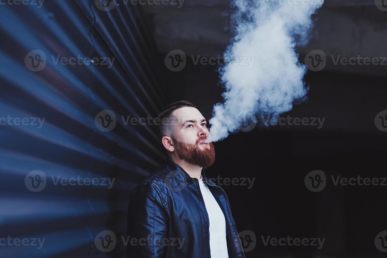 stilig man i en vaping en elektronisk cigarett foto