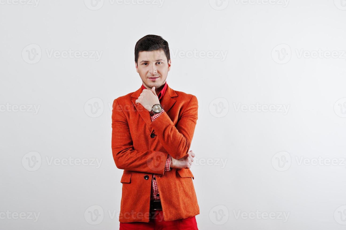 mode ung man i orange kostym och röda byxor avslappnade poser i studio foto