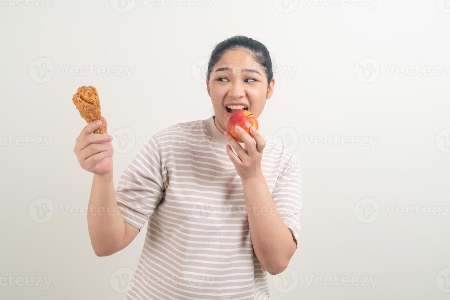asiatisk kvinna med stekt kyckling och äpple till hands foto