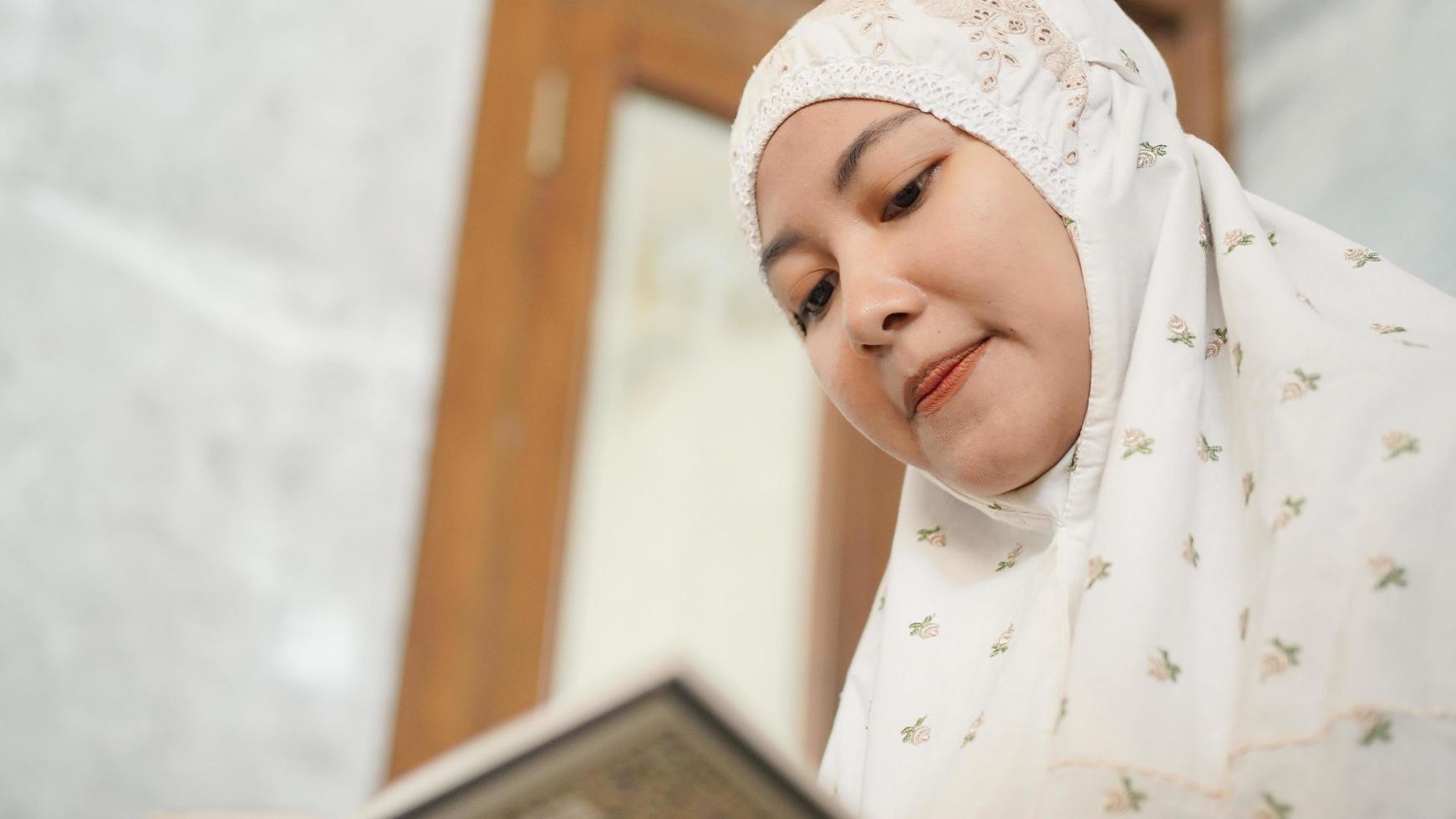asiatisk muslimsk kvinna som läser koranen i moskén foto