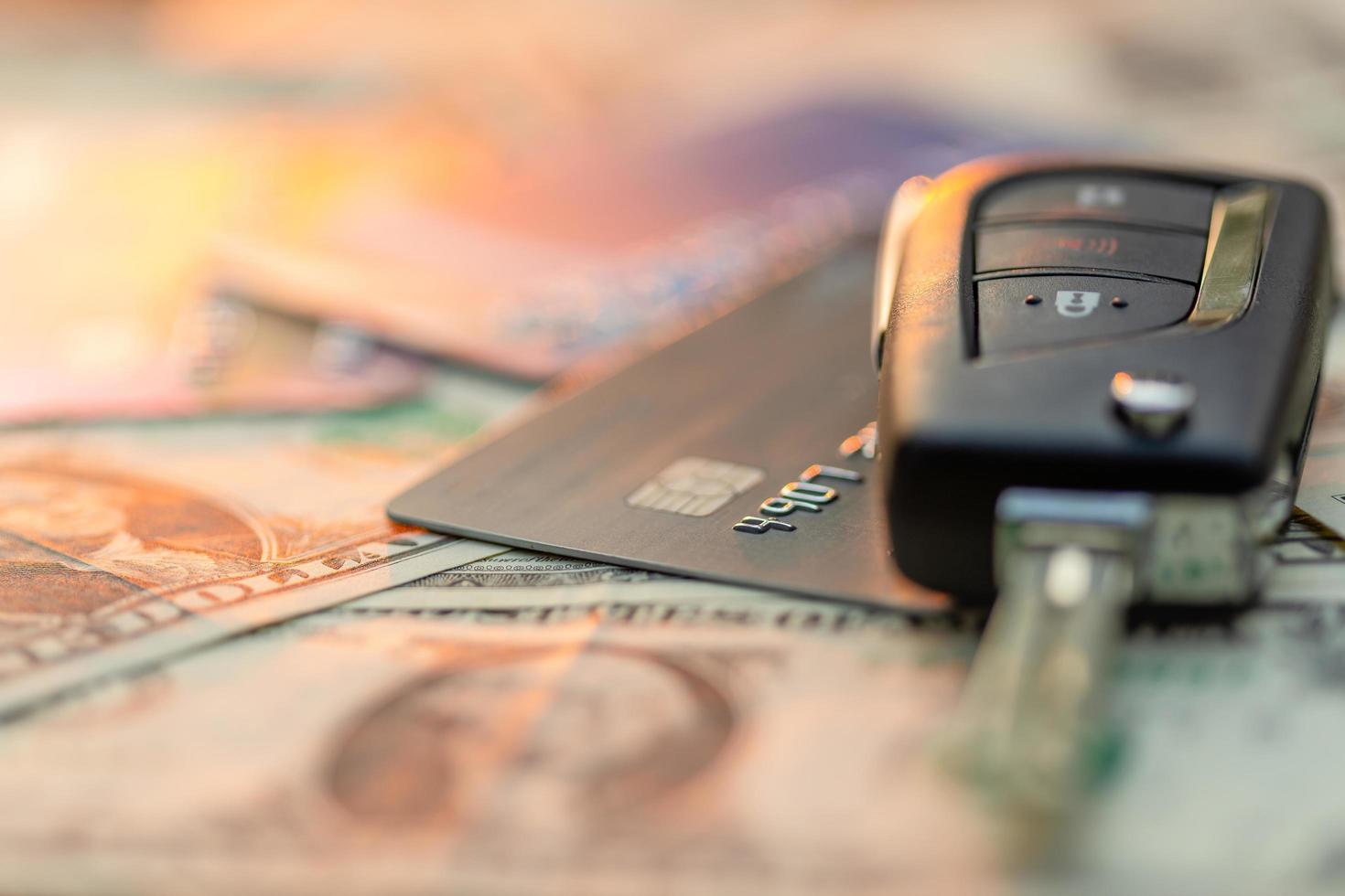nya bilnycklar, kreditkort och amerikanska dollar sedel på träbord. bilköp eller biluthyrningskoncept foto