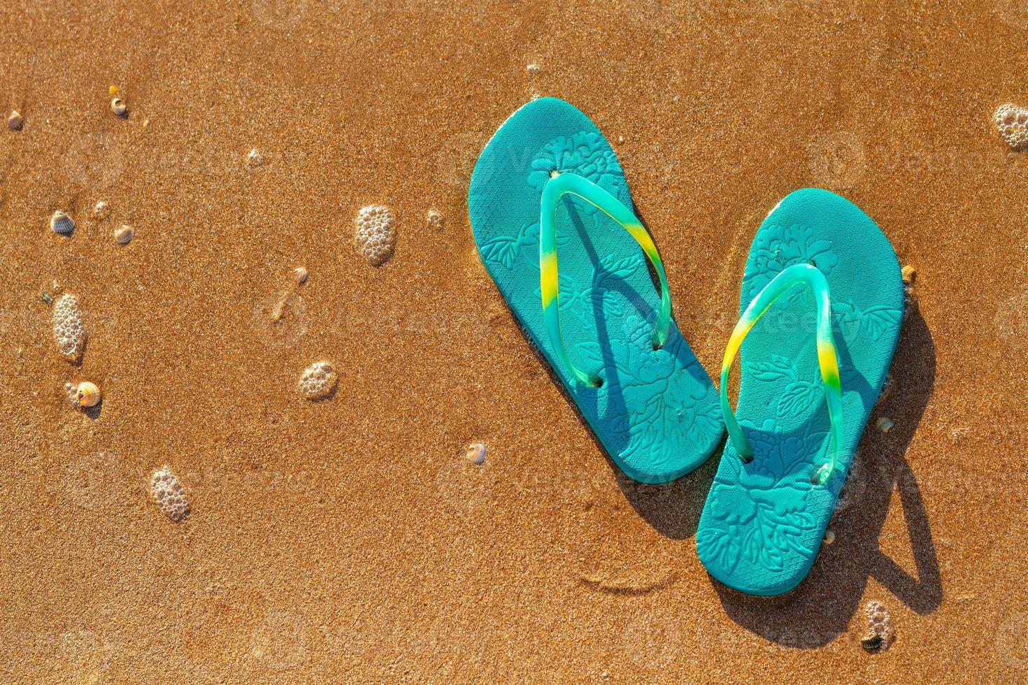 kvinnors flip flops stå på stranden på sanden, semester koncept foto