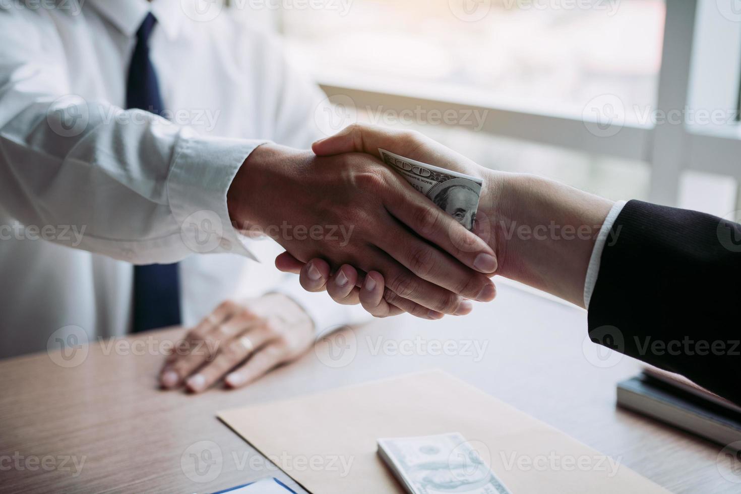 två företags affärsmän skakar hand medan en man placerar pengar på dokument i kontorsrum med korruptionskoncept. foto