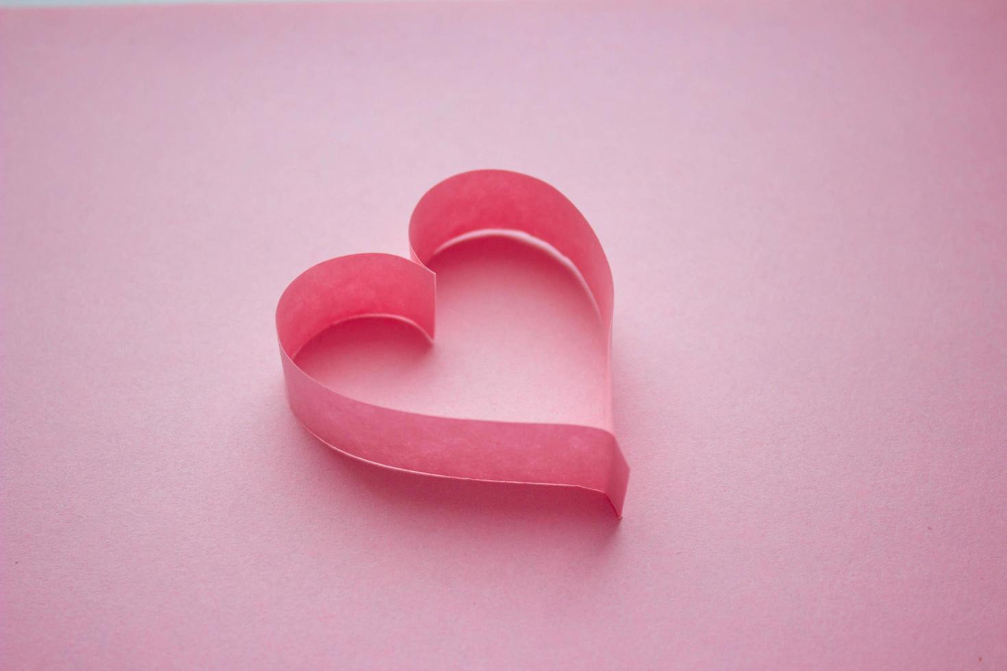 vackert rosa pappershjärta på rosa bakgrund med kopia utrymme. quilling, origami, handgjorda. minimalism foto