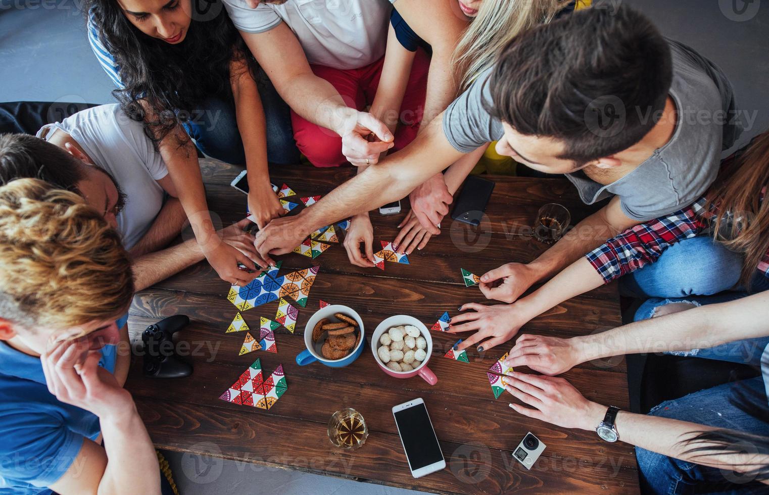 ovanifrån kreativt foto av vänner som sitter vid träbord. ha kul när du spelar brädspel