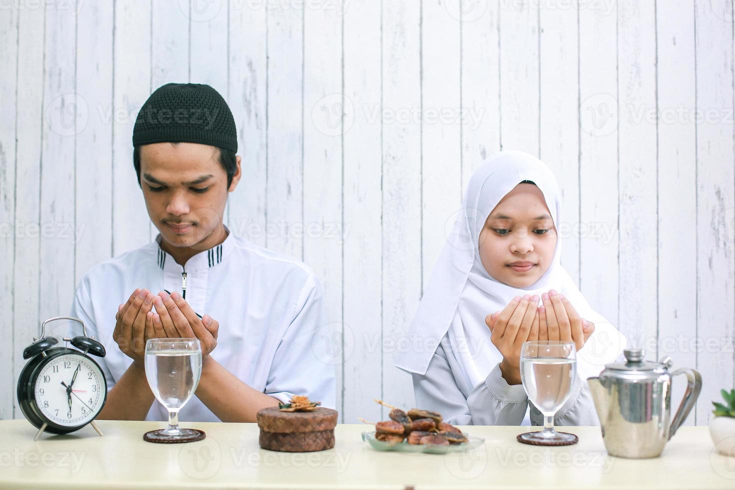 suddigt foto av muslimska par som ber tillsammans vid iftar tid.