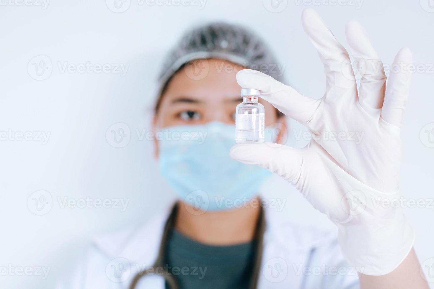 asiatisk kvinnlig läkare eller forskare som bär mask med medicinflaska i handen på vit bakgrund. medicin, vaccination, immunisering och hälsovårdskoncept foto