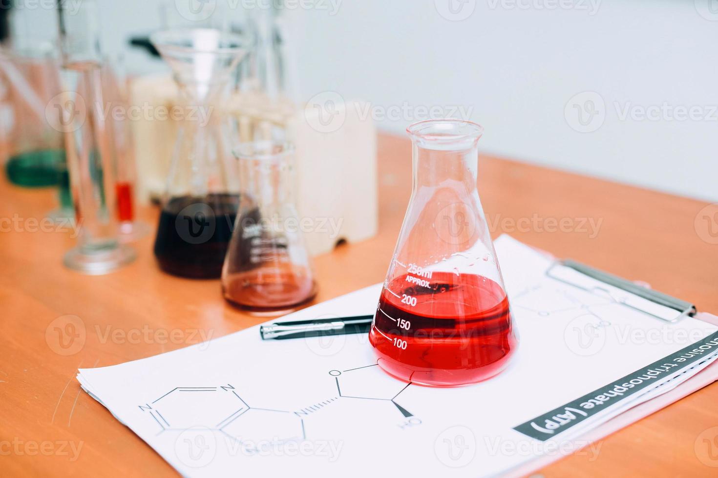 röd vätska på bägare med labbutrustning på bordet. nationella vetenskapsdag, världsvetenskapsdag foto
