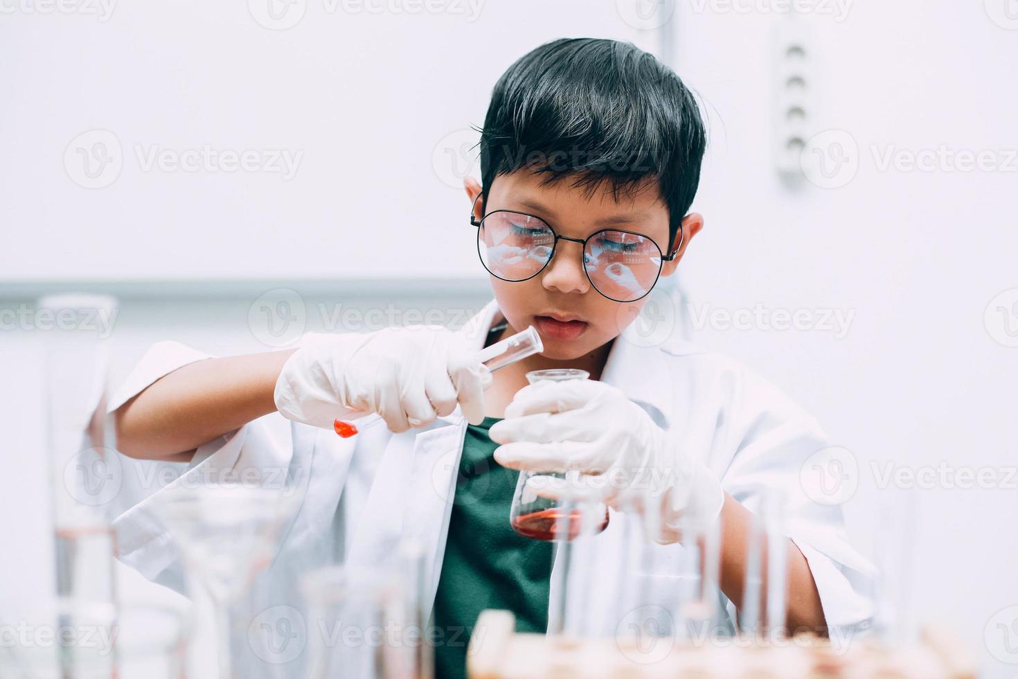 skolläkarstudent som häller vätska i glasvarorna i laboratoriet. nationella vetenskapsdag, världsvetenskapsdag foto