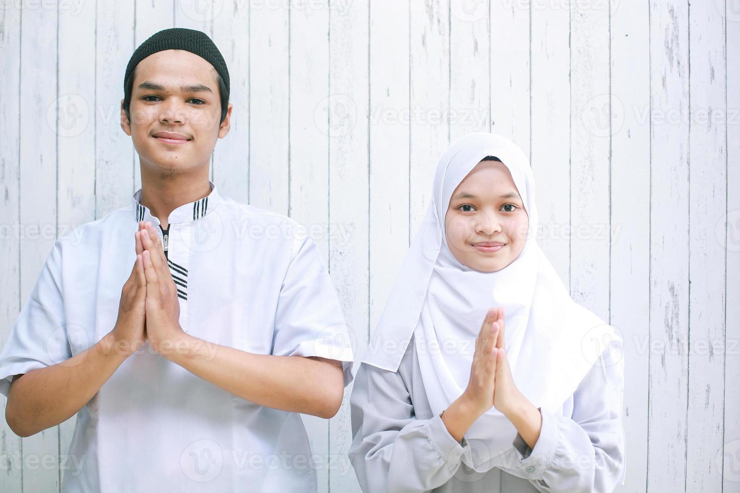 asiatiskt muslimskt par gör muslimskt handslag i kameran för att välkomna gäster eller hälsa på eid mubarak-firandet foto