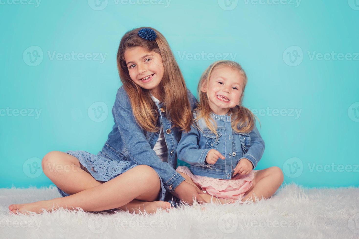 leende systrar sitter på golvet foto