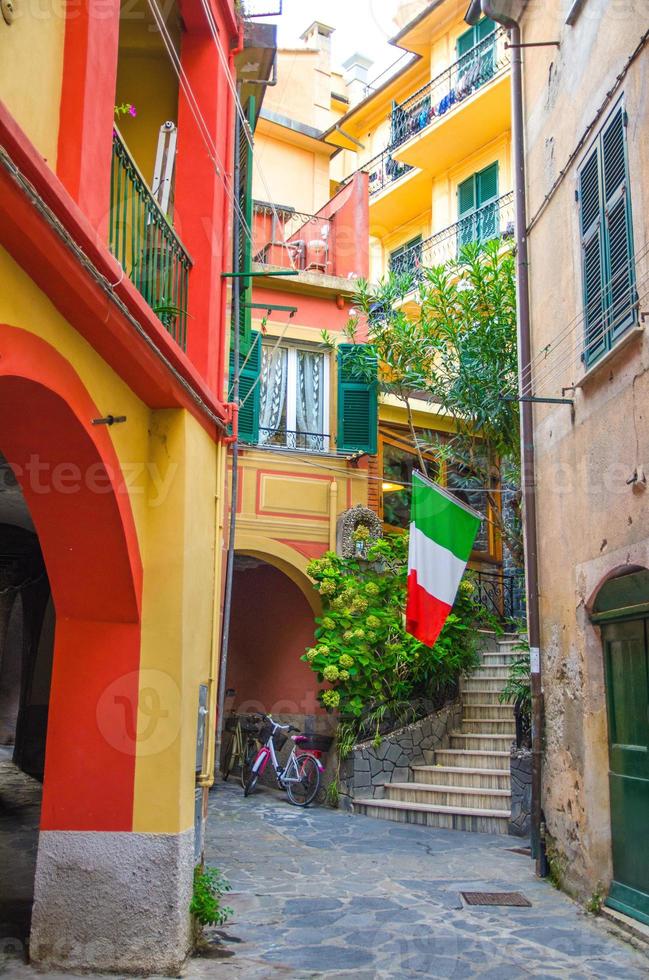 typisk liten italiensk gård med byggnadshus, trappor, slutarfönster och italiensk flagg i byn Monterosso foto