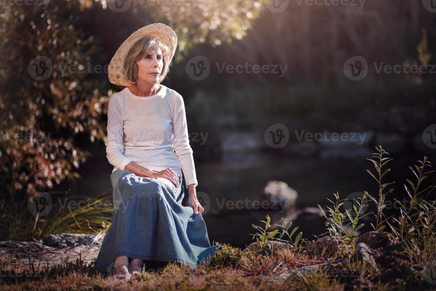 senior kvinna sitter på fältet foto