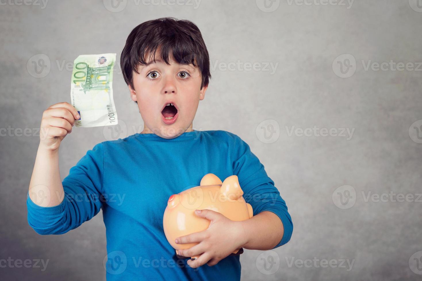 förvånat barn som sparar pengar i en spargris foto