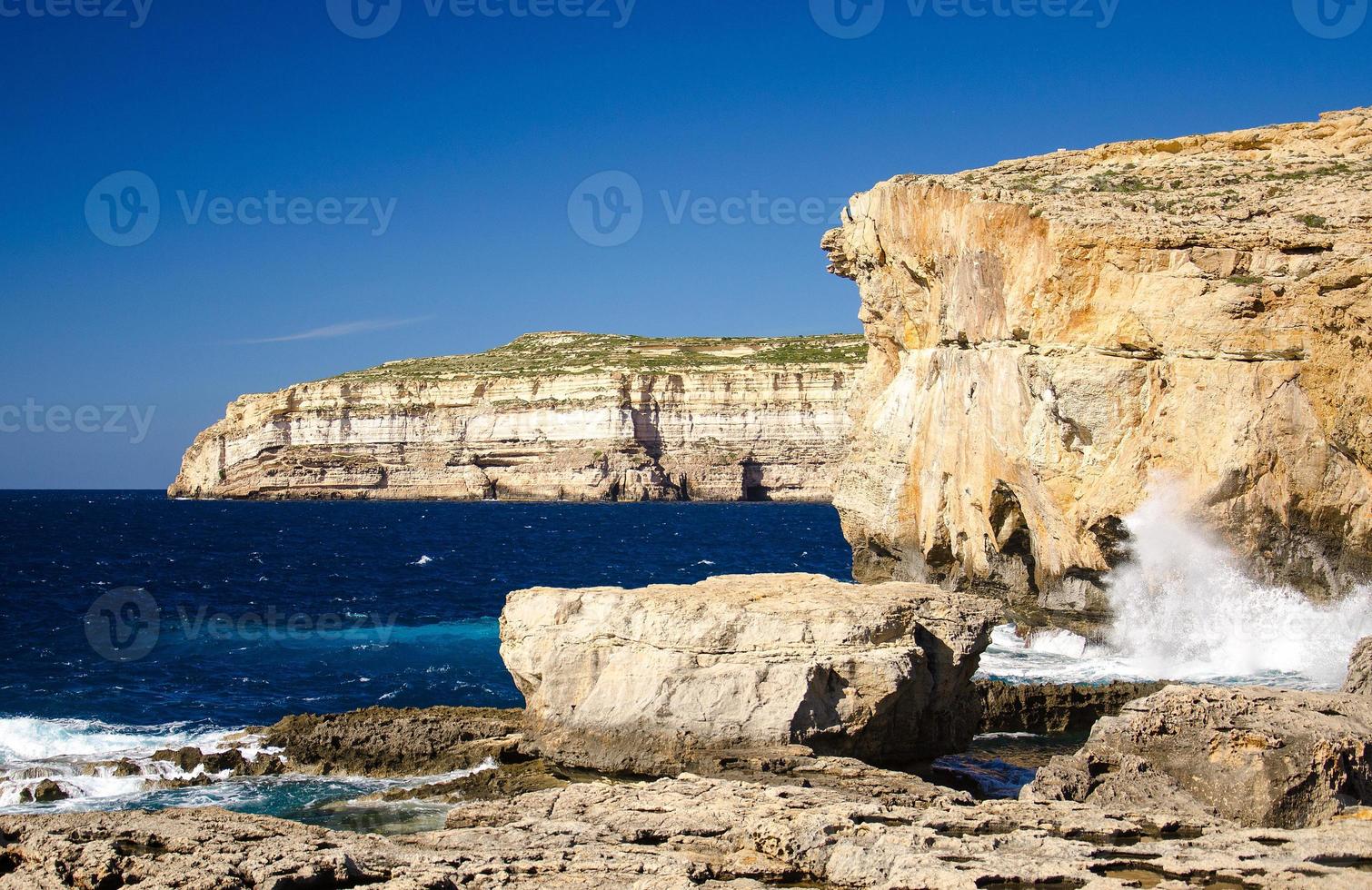 stenig kustlinje klippor nära kollapsade azurblå fönster, gozo island, malta foto