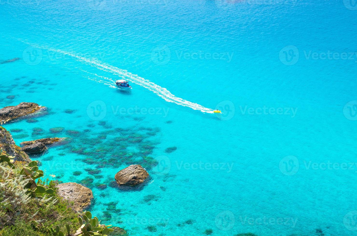 fiskeyacht och gummibåt i capo vaticano lagunen, Kalabrien, Italien foto