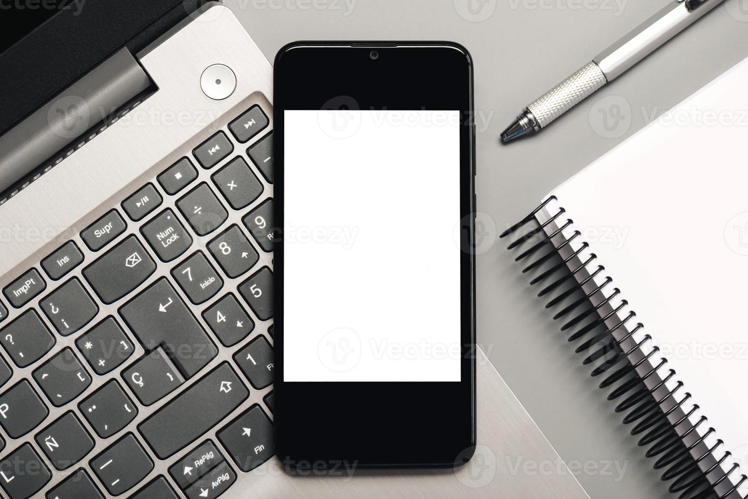 smartphone med vit skärm för kopieringsutrymme med bärbar dator och anteckningsbok foto