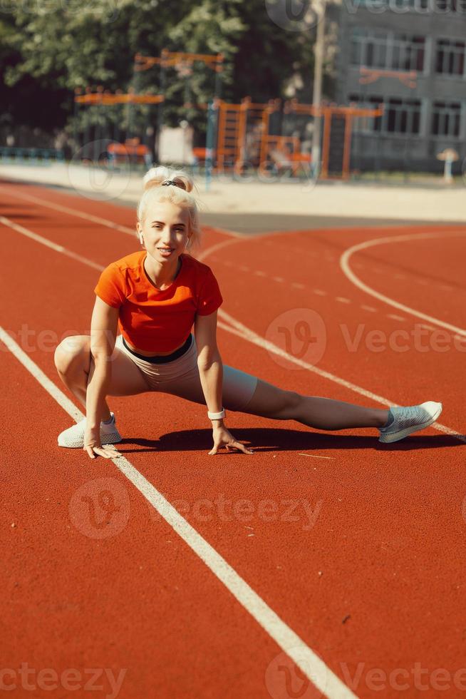 ung vacker flicka gör uppvärmning innan sport träning på skolans stadion foto