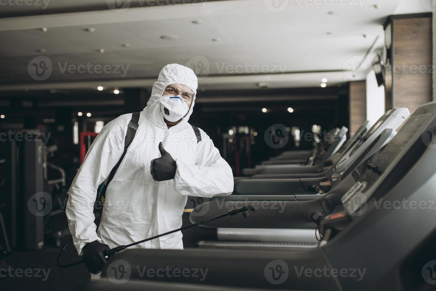 rengöring och desinfektion på trånga platser mitt i coronaepidemin gym rengöring och desinfektion förebyggande och kontroll av epidemin. skyddsdräkt och mask och spraypåse foto