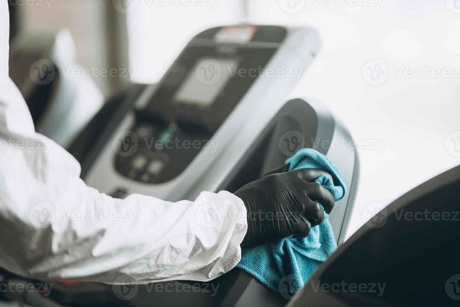 rengöring och desinfektion på trånga platser mitt i coronaepidemin gym rengöring och desinfektion förebyggande och kontroll av epidemin. skyddsdräkt och mask och spraypåse foto