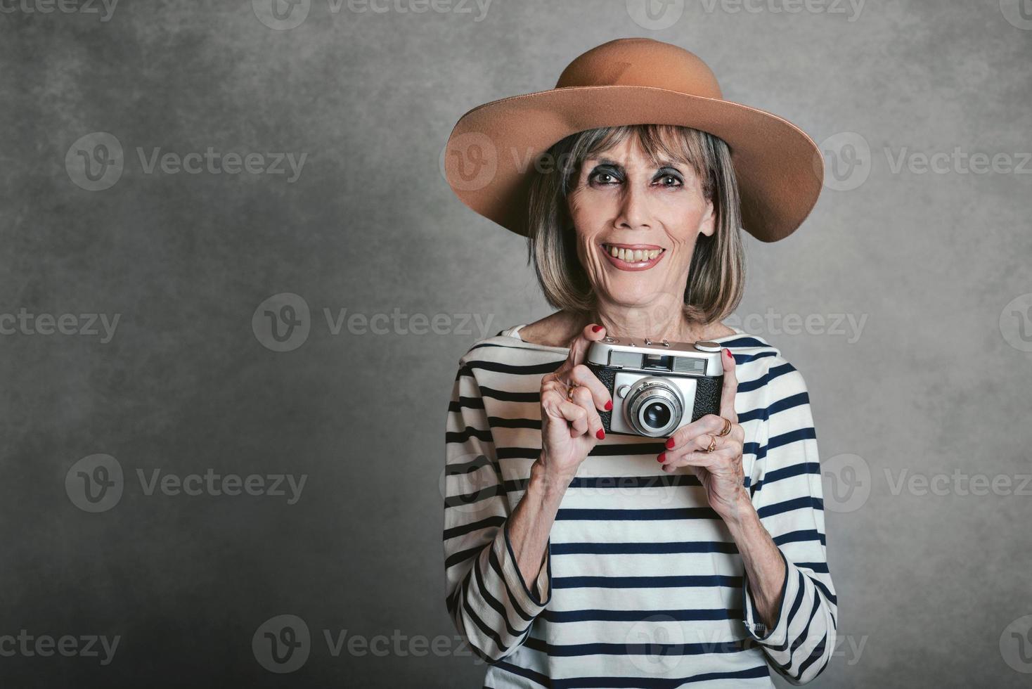 porträtt av leende äldre kvinna med vintage fotokamera foto