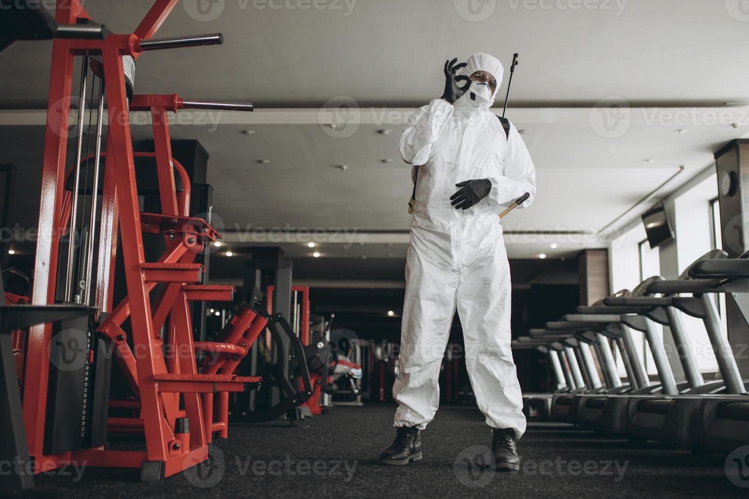 rengöring och desinfektion på trånga platser mitt i coronaepidemin gym rengöring och desinfektion förebyggande och kontroll av epidemin. skyddsdräkt och mask och spraypåse foto