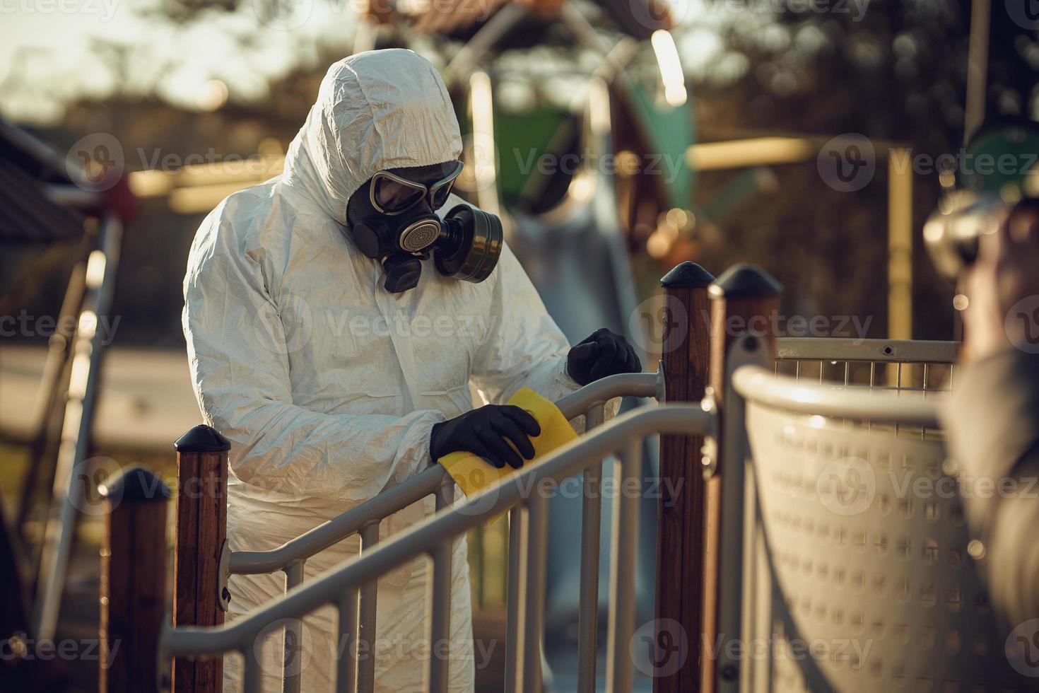 rengöring och desinfektion på lekplatsen i stadskomplexet mitt i coronavirusepidemiteam för desinfektionsinsatser infektionsförebyggande och kontroll av epidemiskyddsdräkt och mask foto