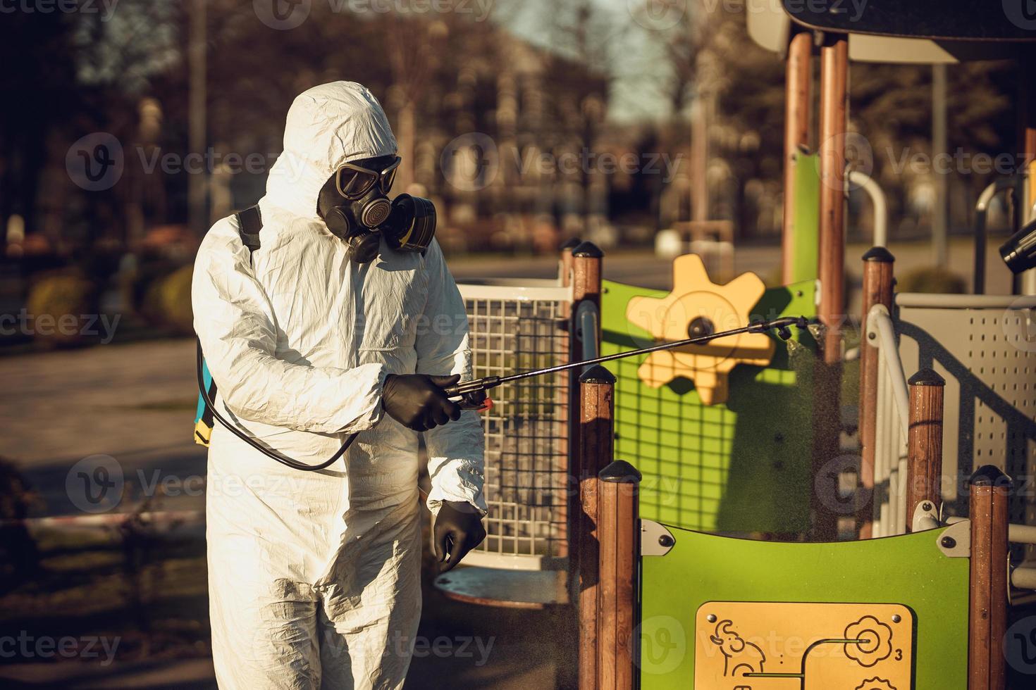 rengöring och desinfektion på lekplatsen i stadskomplexet mitt i coronavirusepidemiteam för desinfektionsinsatser infektionsförebyggande och kontroll av epidemiskyddsdräkt och mask foto