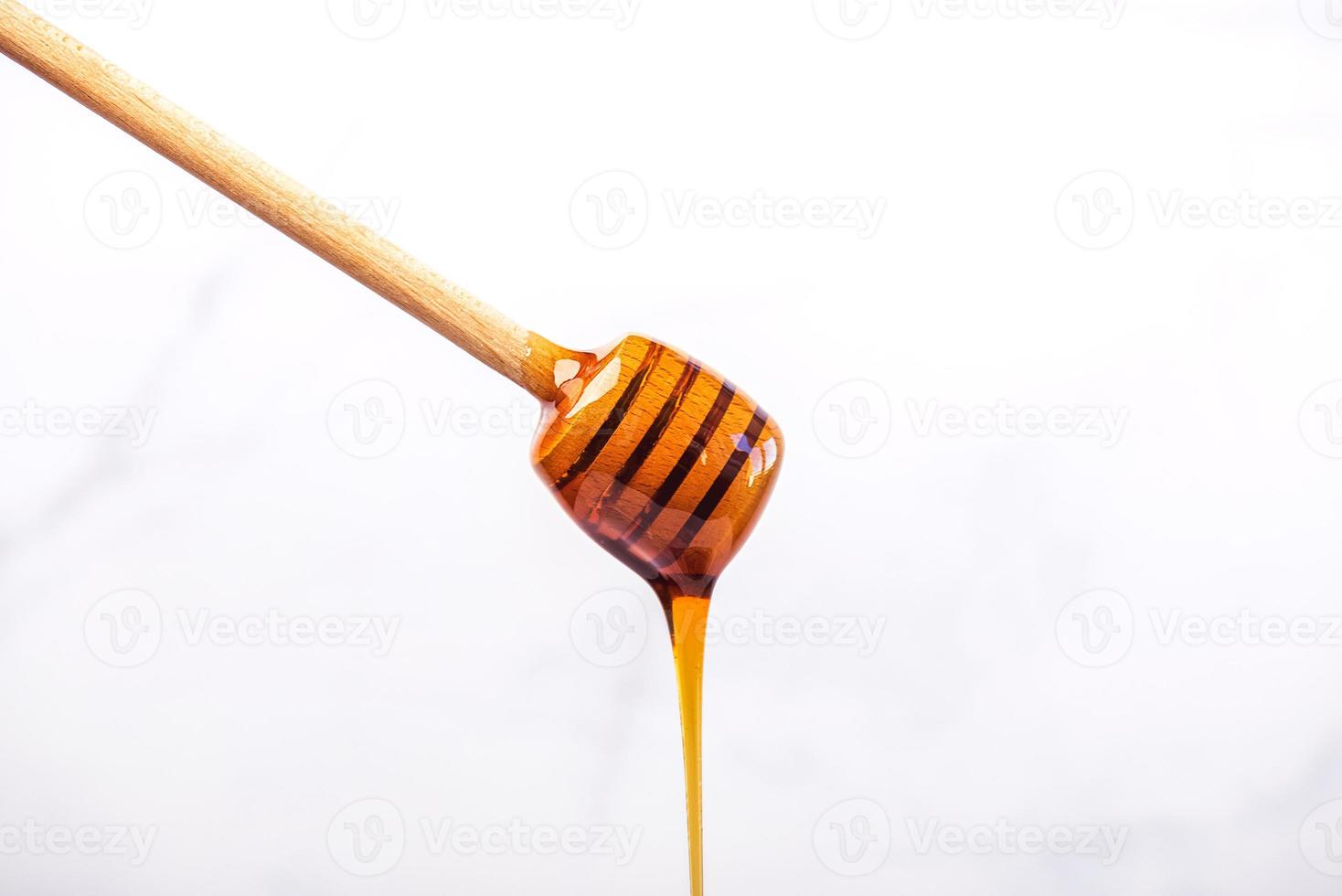 honung som droppar från en träslev för honung foto