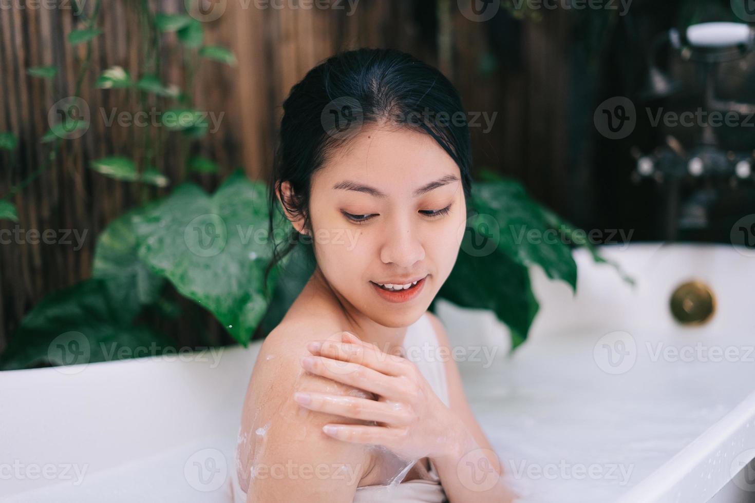 vacker ung asiatisk kvinna som kopplar av i badet foto