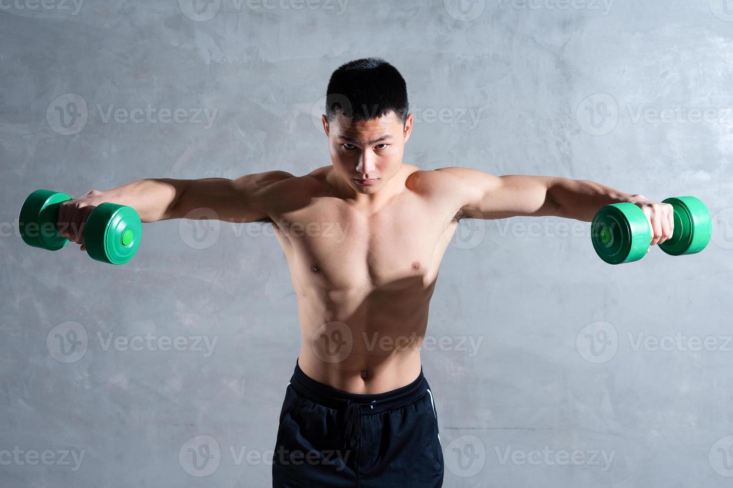 muskulös asiatisk man poserar på grå bakgrund foto