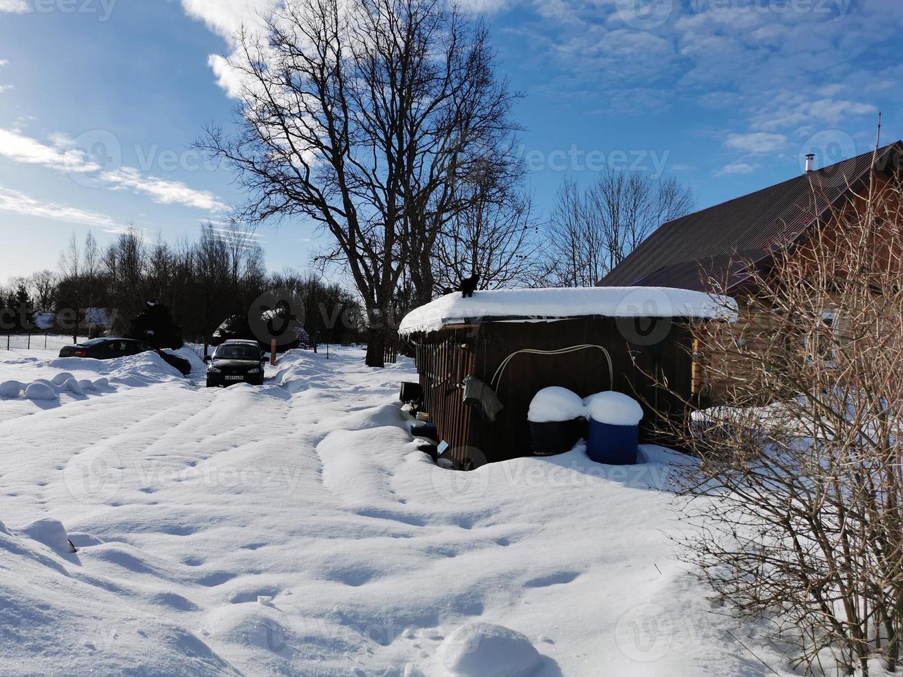 vinterdag i den ryska byn snö väl blå himmel foto