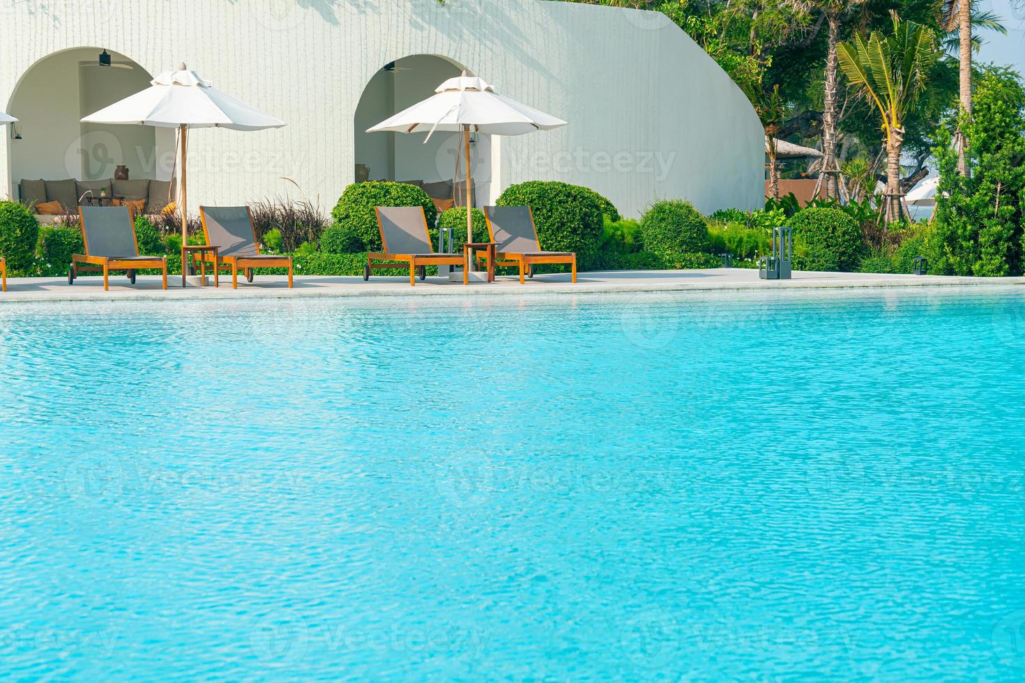 paraply med säng pool runt pool med havet havet bakgrund foto