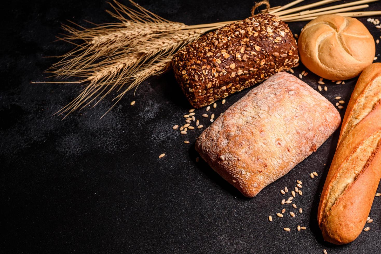 vackert nybakat bröd med vetekorn på en mörk betongbakgrund foto