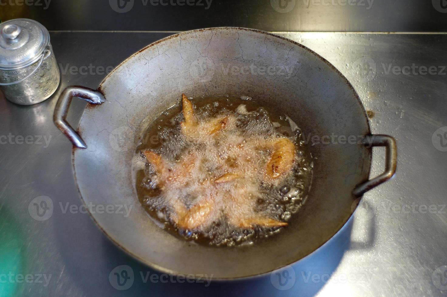 ovanifrån många bitar av kycklingvingar friterade i den kokta vegetabiliska oljan. foto