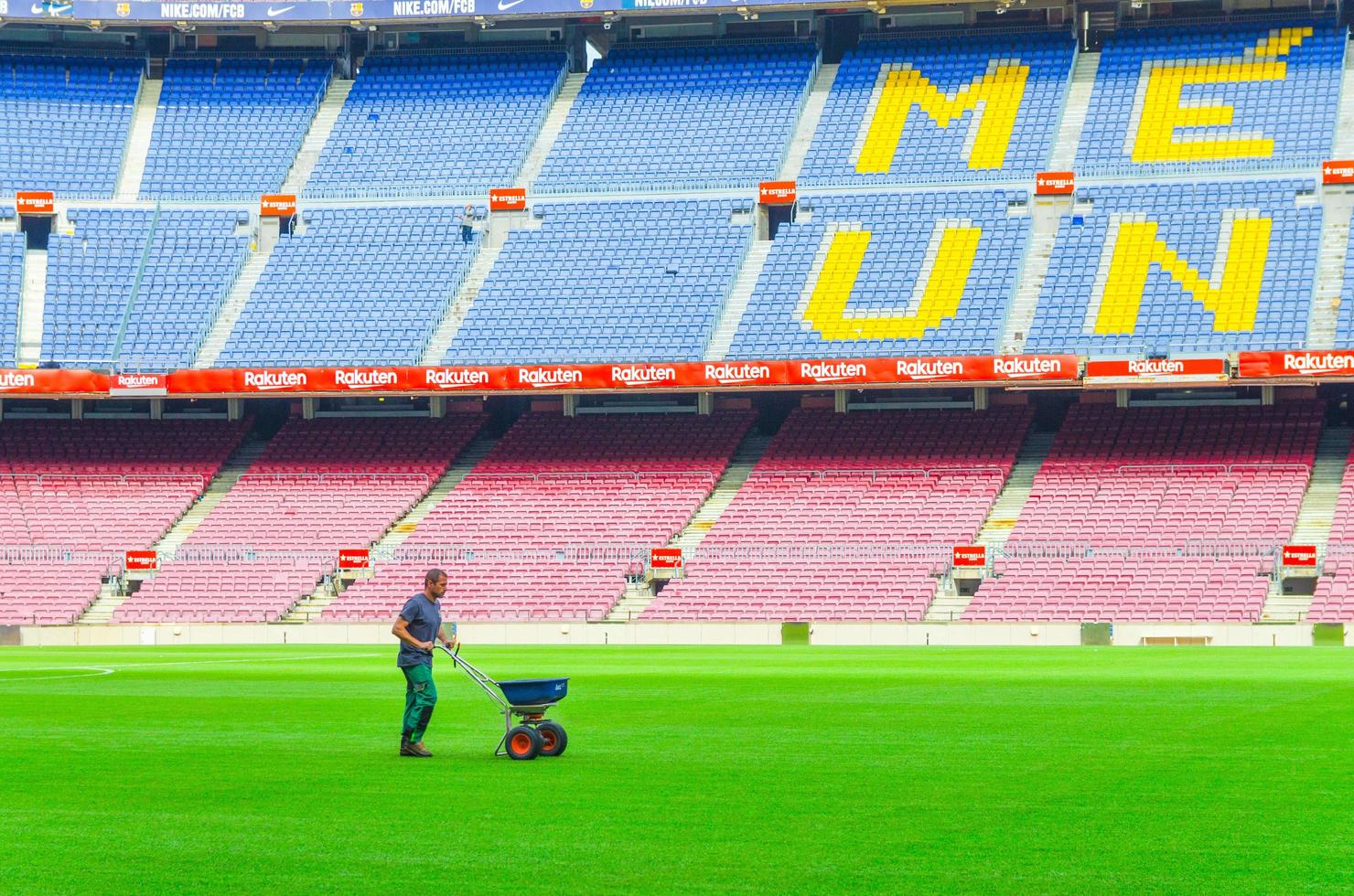 Barcelona, Spanien, 14 mars 2019 arbetare sådd gräs med gödningsspridare på gräsmattan i Camp Nou gröna fält, tribuner står bakgrund. stadion för fotbollsklubben barcelona foto