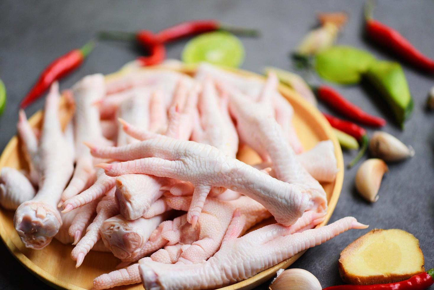 färska råa kycklingfötter för lagad mat på träbord köksbakgrund, kycklingfötter på tallrik foto