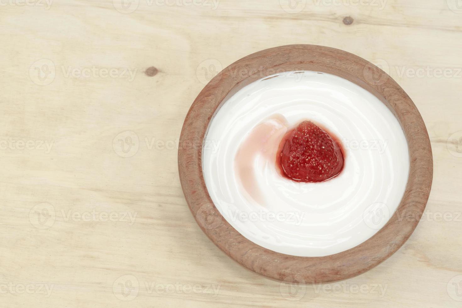 yoghurt i trä kopp har jordgubbar isolerade foto