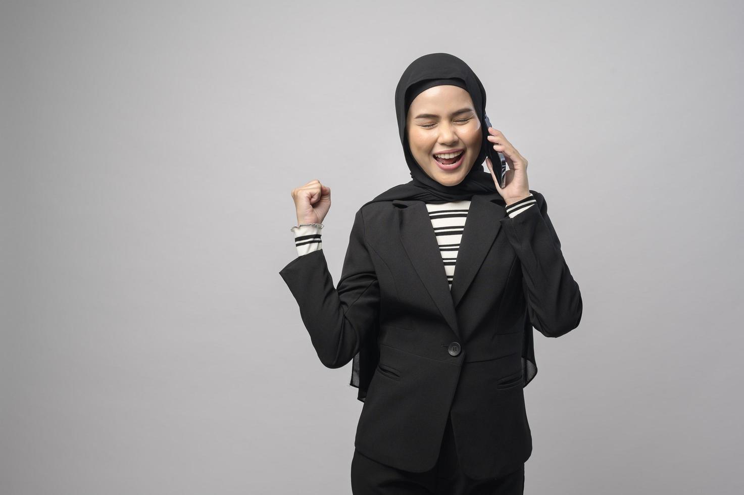 porträtt av vacker kvinna med hijab med mobiltelefon på vit bakgrund foto