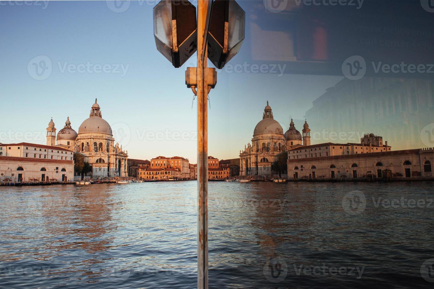 utsikt och reflektion i glaset av den gamla katedralen i santa maria della salute vid solnedgången i Venedig, Italien foto